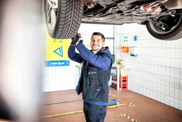 Prüfingenieur untersucht ein Fahrzeug auf der Hebebühne, Prüfhalle von HU Plus in Nürnberg